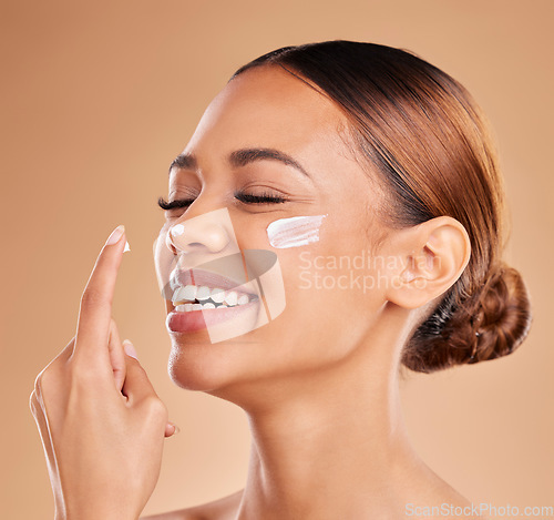 Image of Face, funny skincare and woman with cream in studio isolated on a brown background. Dermatology, beauty cosmetics and happy female model laughing with lotion, creme or moisturizer for skin health.