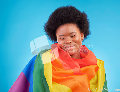 Image of Rainbow, happy and black woman with lgbtq flag in studio for gay community, queer rights and homosexual pride. Free, smile and face of girl for lesbian, bisexual and trans support on blue background