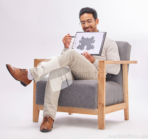 Image of Psychology, psychologist and man with rorschach test diagram on clipboard in studio isolated on a white background. Therapist, consultant or happy male sitting on chair with document for inkblot exam