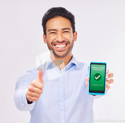 Image of Asian man, portrait and phone with thumbs up for transaction approval against a white studio background. Happy male smile showing thumb emoji, yes sign or like for electronic purchase on smartphone