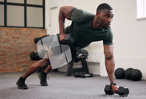 Image of Black man, dumbbell row and training in gym, workout and strong fitness in health club. Serious sports athlete, bodybuilder and weight exercise on ground for energy, power and core strength challenge