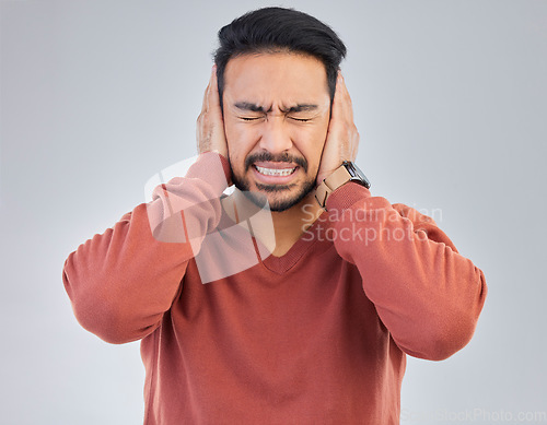 Image of Asian man, frustrated and cover ears in studio for sound noise, mental health and headache by gray background. Young student guy, panic attack or anxiety with hands on head with anger, stress or fail