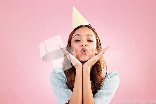 Image of Birthday woman, face portrait and kiss for celebration event, congratulations or celebrate studio happiness. Emoji gesture, party hat and headshot female, person or young model on pink background