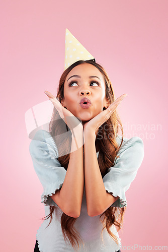 Image of Birthday woman, studio and blowing kiss for celebration event, congratulations or celebrate happiness. Emoji gesture, party hat and relax female, person or young model looking on pink background