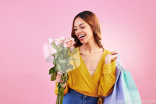 Image of Happy, shopping bags and smile with woman and flowers in studio for retail, birthday and spring. Event, party and celebration with female and roses on pink background for sale, discount and romance