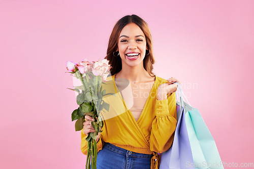 Image of Happy, shopping bags and flowers with portrait of woman in studio for retail, birthday and spring. Event, party and smile with female and roses on pink background for sale, discount and romance
