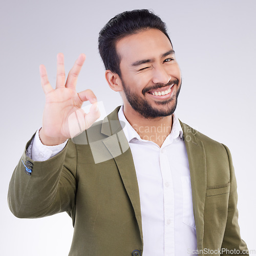 Image of OK hand, portrait and business man isolated on a white background career, job success and agreement with wink. Like, yes and okay sign or emoji of asian person, entrepreneur or worker face in studio