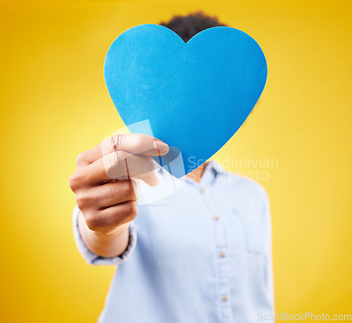 Image of Paper, heart and hide with woman in studio for romance, positive and emotion. Happiness, love shape and giving with female isolated on yellow background for date, feelings and affectionate