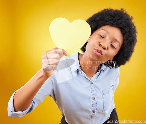 Image of Paper, heart and kiss with black woman in studio for romance, positive and emotion. Happiness, love shape and giving with female isolated on yellow background for date, feelings and affectionate