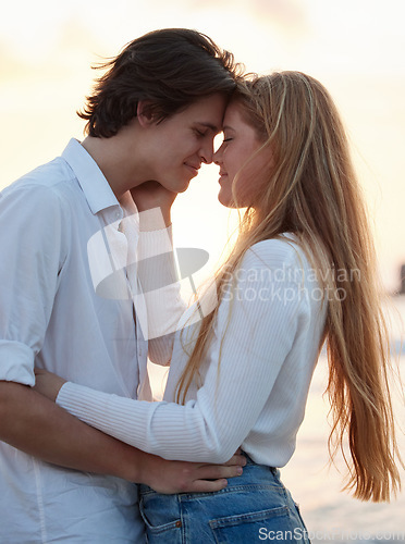 Image of Love, kiss and sunset with couple at beach for romance, relax and vacation trip. Travel, sweet and cute relationship with man and woman hugging on date for summer break, affectionate and bonding