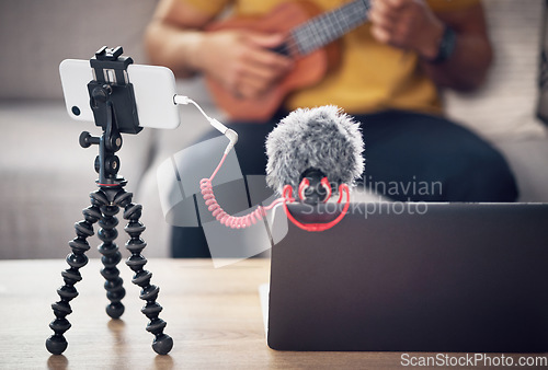 Image of Laptop, phone and music influencer, man with ukulele on sofa, webinar recording and live streaming in home. Internet, webcam and online content creation equipment for social media tutorial channel.