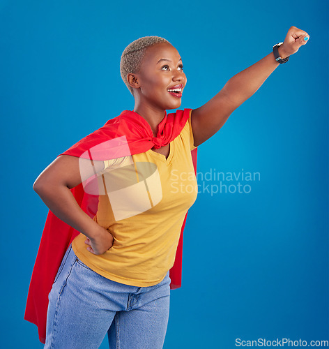 Image of Black woman, superhero cape and flying in studio, blue background and pop culture fashion. Happy female model, cosplay character and superwoman costume of fist, courage or action of strong girl power