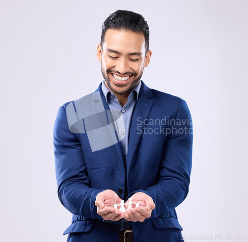 Image of Insurance, trust and financial security with a business man holding a paper cutout of a family on a studio gray background. Future, safety and life cover with a handsome young male broker or agent