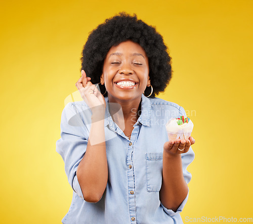 Image of Birthday, wish and cupcake with a black woman on a yellow background in studio for celebration. Happy, smile and dessert with an attractive young female celebrating a special event on a color wall