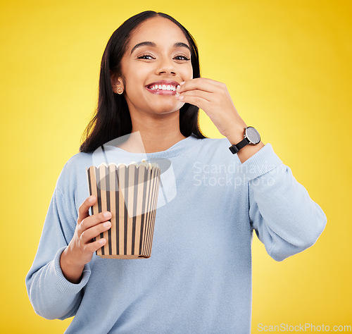 Image of Woman is eating popcorn, happiness and portrait with snack for watching tv or movie on yellow studio background. Streaming service, film and food with corn treat, young female with smile and cinema