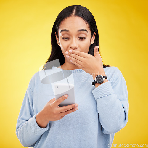 Image of Shock, surprise and woman in studio with phone and hand on mouth isolated on yellow background. Social media, fake news or exciting online promotion, hispanic girl reading notification on smartphone.