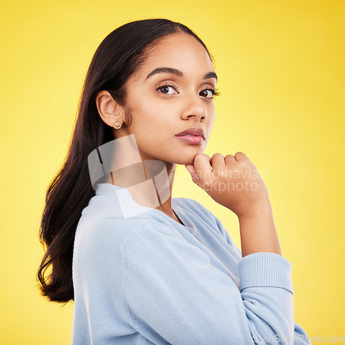 Image of Portrait, thinking and a woman on a yellow background in studio feeling thoughtful or contemplative. Face, idea and an attractive young female standing hand on chin while contemplating a thought