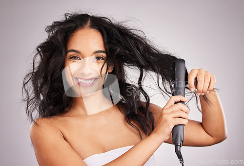 Image of Portrait, happy woman and hair straightener for beauty in studio, treatment and wellness on background. Female model, haircare and heat styling equipment for ironing curly hairstyle, texture or tools