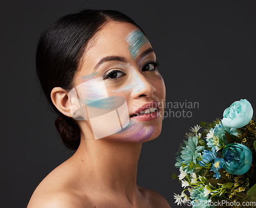 Image of Beauty, woman and face paint with makeup, art with flowers and colorful aesthetic, color stroke in portrait on studio background. Skin, glow and cosmetics with creativity and female with smile