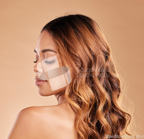 Image of Beauty, haircare and face of woman with curls in studio for growth shine with strong texture on brown background. Aesthetic female with long, color and healthy hair over shoulder after salon care