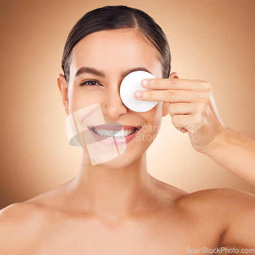 Image of Portrait, cotton pad and woman with skincare, dermatology and happiness against a brown studio background. Face cleaning, female and lady with cosmetics tool, treatment and grooming to remove makeup