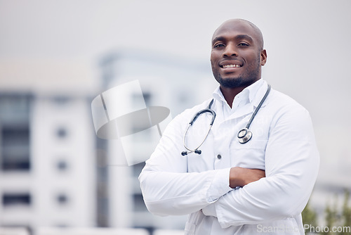 Image of African, man and doctor in city for portrait, arms crossed and smile for wellness, healthcare and mockup. Young black medic, confidence and happy in metro with blurred background for mock up space