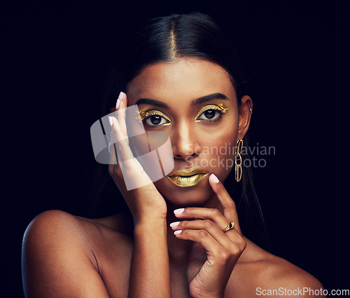 Image of Gold makeup, serious and portrait of a woman isolated on a black background in a studio. Beauty, young and glamorous Indian model posing with creative cosmetics, jewelry and stylish on a backdrop