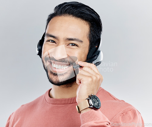 Image of Asian man, portrait smile and headphones with mic for call center or online customer service against a white studio background. Happy male consultant with headset smiling for wireless communication