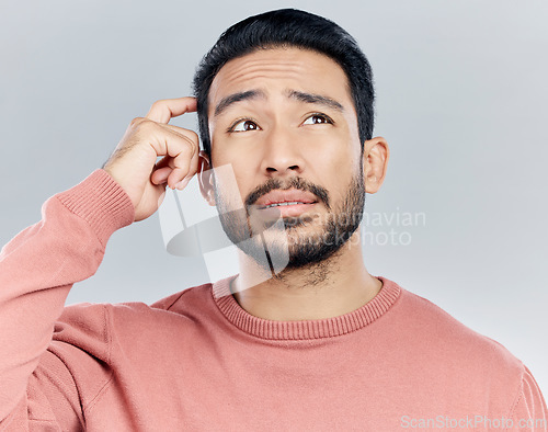 Image of Thinking, confused and doubt with a man in studio on a gray background looking thoughtful or contemplative. Question, idea and memory with a young asian male trying to remember but feeling unsure