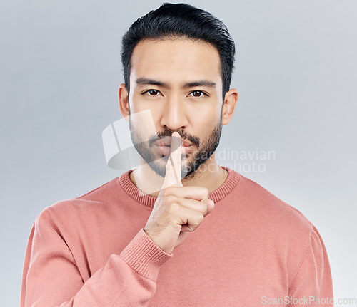 Image of Secret, finger on lips and portrait of man in studio with privacy, silence and confidential hand gesture. Communication mockup, emoji and face of male on grey background for shush, whisper or gossip