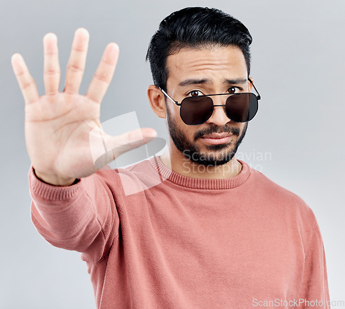 Image of Stop, portrait and a cool man with sunglasses isolated on a white background in a studio. No, rejection and an Asian guy with a hand sign for warning, security and bouncer with decline on a backdrop