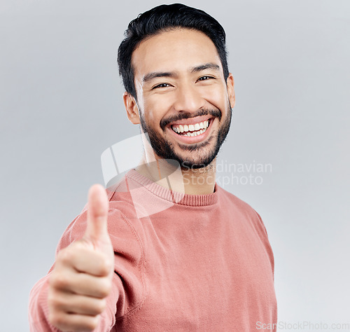 Image of Asian man, portrait smile and thumbs up for success, good job or winning against a white studio background. Happy male face smiling and showing thumb emoji, yes sign or like for agreement or approval