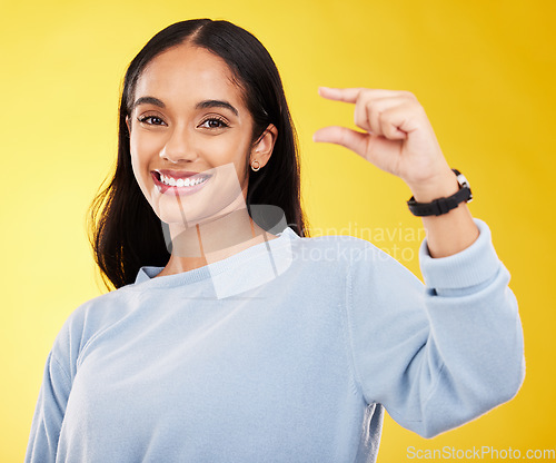 Image of Showing, small and portrait of a woman with hands isolated on a yellow background in a studio. Happy, measurement and a girl with a review, gesturing size and opinion with fingers on a backdrop