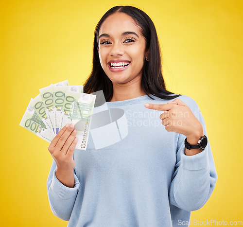 Image of Woman, happy and cash in studio portrait for bonus, winning or profit by yellow background. Young student girl, winner and money fan with pointing at bills for celebration of success on stock market