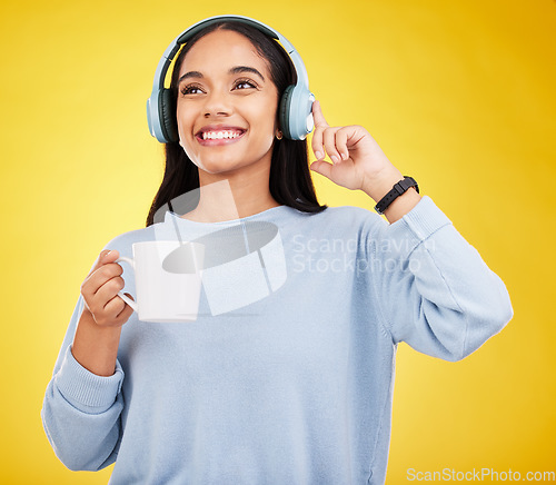 Image of Coffee, music and headphones with woman in studio for streaming, online radio and relax. Smile, media and podcast with female isolated on yellow background for technology, listening and connection