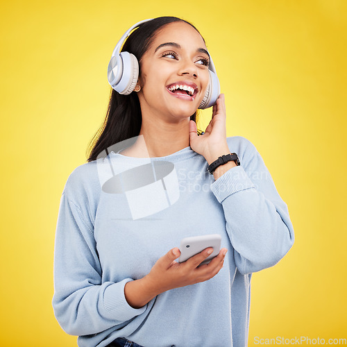 Image of Happy, music and phone with woman in studio for streaming, online radio and audio. Smile, media and podcast with female and headphones on yellow background for technology, listening and connection