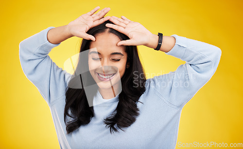 Image of Happy, dance and face of woman on yellow background for positive mindset, happiness and freedom. Smile, mockup space and isolated girl with hands on head for dancing, relaxing and calm in studio