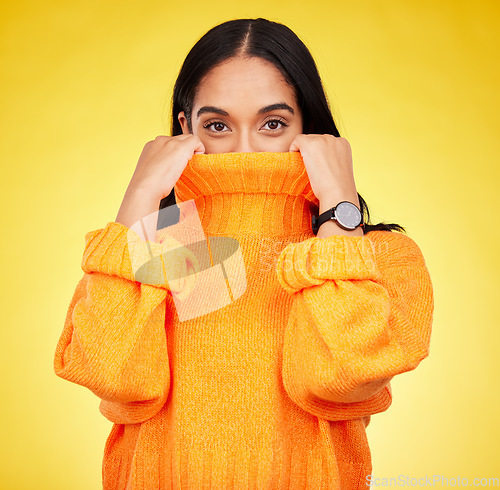 Image of Cold, cover and portrait of a woman with a jersey isolated on a yellow background in a studio. Hiding, winter and a girl holding a jumper up for covering, warmth and bad weather on a backdrop