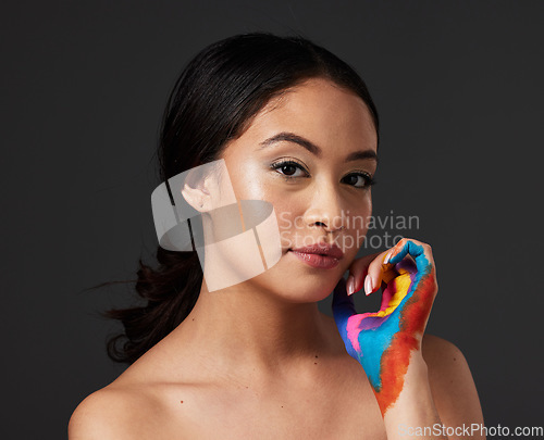 Image of Woman, portrait and beauty with rainbow paint hand and skincare for serious face in studio. Creative skin and makeup on female aesthetic model on gray background for lgbtq color inspiration on hands