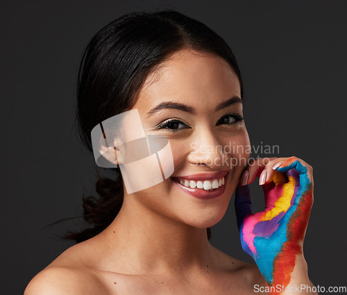 Image of Woman, portrait and beauty smile with rainbow paint hand or art on and face in studio. Creative skin and makeup on female aesthetic model on gray background for lgbtq color inspiration on hands