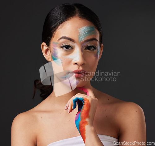 Image of Beauty, portrait and woman with paint art on hand and face in studio. Creative skin and rainbow makeup on serious female aesthetic model on gray background for lgbtq color inspiration on hands