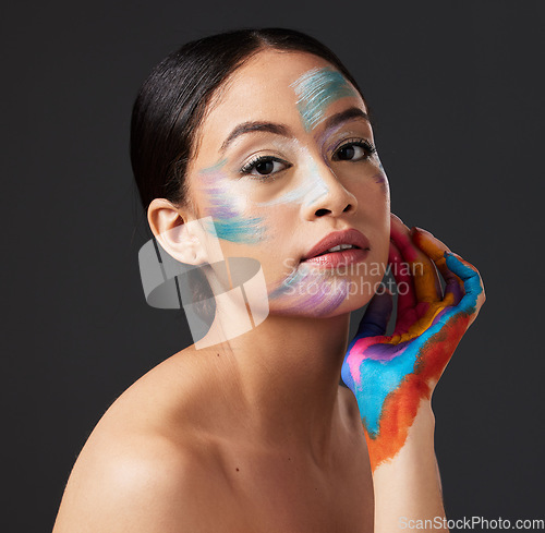 Image of Woman, portrait and beauty with rainbow makeup art on hand and face in studio. Creative skin and facial cosmetics on female aesthetic model on gray background for lgbtq color inspiration on hands