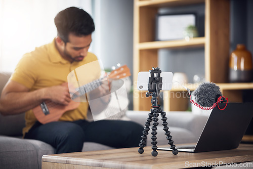 Image of Streaming, ukulele and phone with a man online to coach during live lesson. Asian male person on home sofa with a guitar as content creator or influencer teaching music on education podcast blog