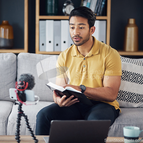 Image of Podcast, bible and man reading with phone and microphone online while live streaming. Asian male on home sofa with Christian religion book as blog content creator or influencer teaching or studying