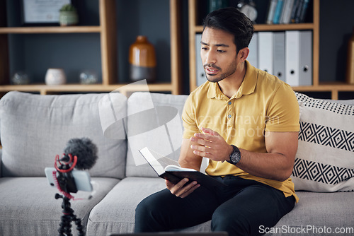 Image of Podcast, bible study and phone with a man online to preach or reading while live streaming. Asian male on home sofa with Christian scripture or book as content creator teaching on education religion
