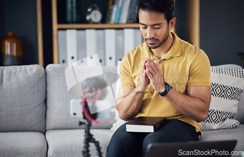 Image of Podcast, bible and man pray with a phone and microphone online while live streaming. Asian male on home sofa to pray with hands and Christian religion book as blog content creator or influencer