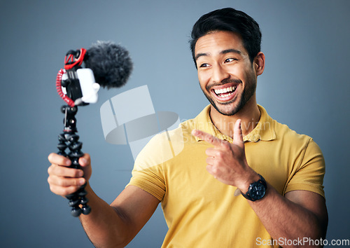 Image of Phone, content creation and Indian man in studio with smile, webinar recording and live streaming on grey background. Internet, webcam and happy online influencer with smile on social media channel.