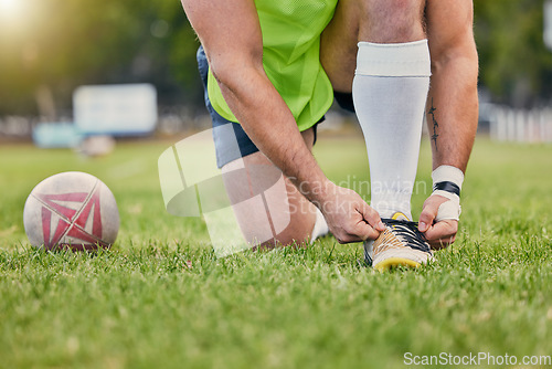 Image of Rugby ball, hands and tying shoe lace on grass field getting ready for sports match or game outdoors. Hand of sporty man tie shoes in preparation for sport, performance or motivation in park