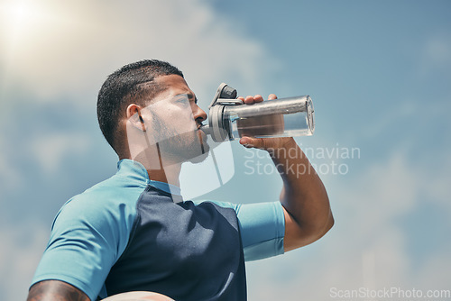Image of Drinking water, fitness and training with a sports man outdoor for a competitive game or event. Exercise, hydration and health with a male athlete taking a drink from a bottle during a break or rest