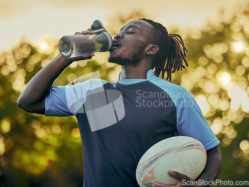 Image of Drinking water, fitness and rugby with a sports black man outdoor for a competitive game or event. Exercise, training and health with a male athlete taking a drink from a bottle during a break